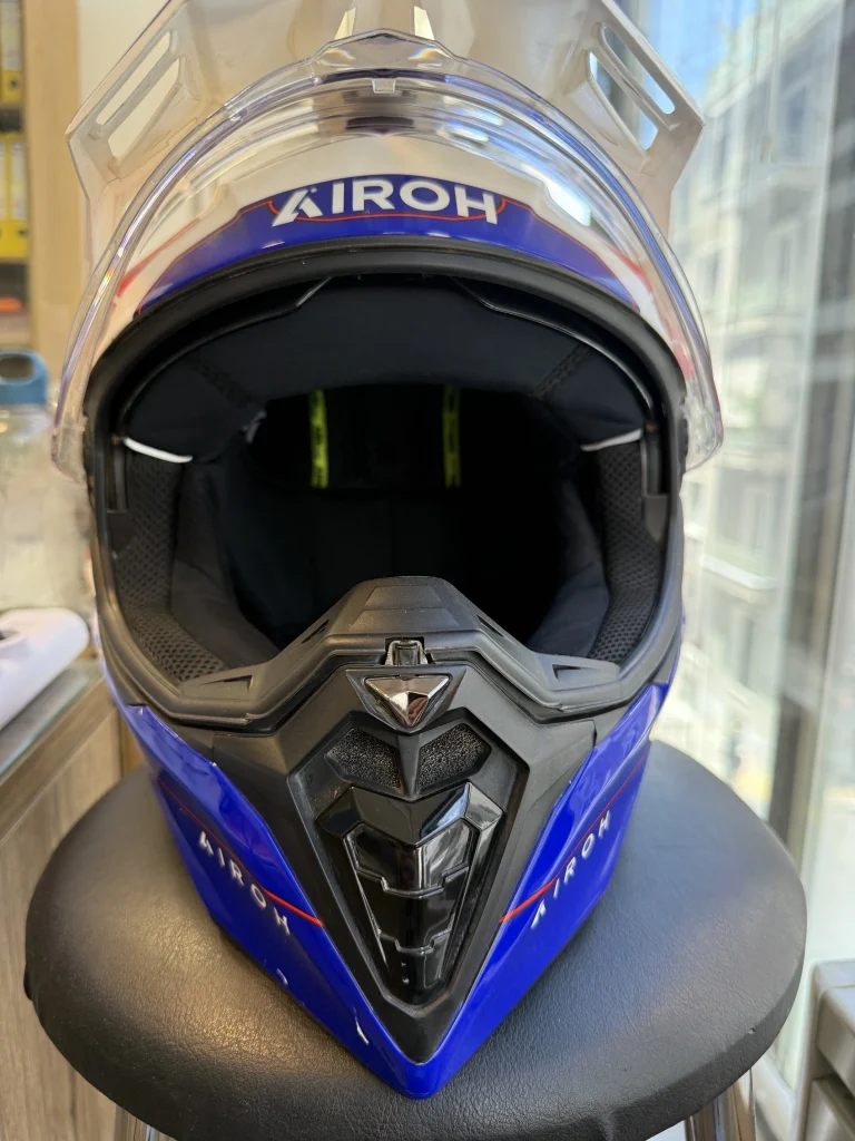 Μπροστινή όψη του κράνους Airoh Commander 2 Reveal Blue Red Gloss, με εμφανές το γείσο, τη μεγάλη ζελατίνα, τον αεραγωγό στο σαγόνι και τα μπλε-κόκκινα γραφικά.