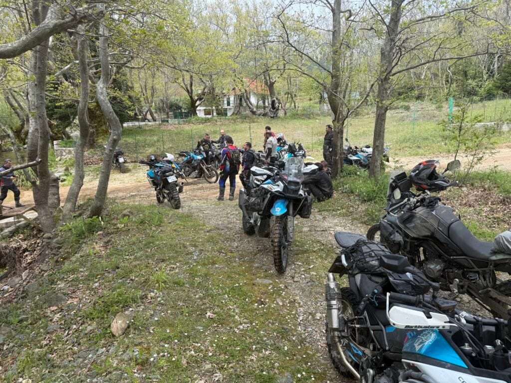 Ομάδα μοτοσυκλετών CFMOTO 450MT σταματημένες σε χωμάτινο άνοιγμα μέσα σε δάσος, κατά τη διάρκεια off‑road ομαδικής διαδρομής στην Εύβοια.