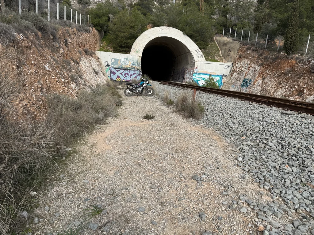 adventure μοτοσυκλέτα CFMOTO 450MT δίπλα σε τούνελ τρένου σε χωματόδρομο