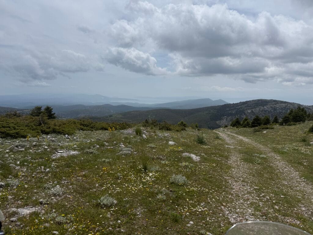 Χωμάτινη off‑road διαδρομή σε αλπικό τοπίο κοντά στον Νέο Κήρικο στην Εύβοια, με κυλιόμενες κορυφογραμμές και σύννεφα πάνω από το βουνό.