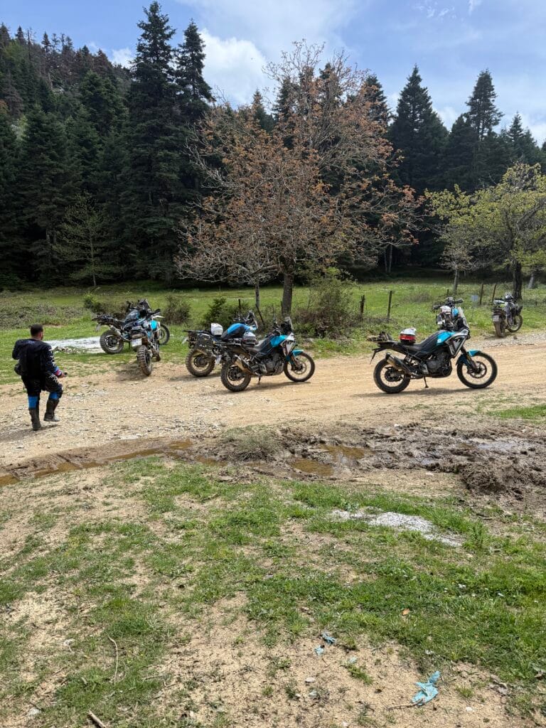 Ομάδα μοτοσυκλετών CFMOTO 450MT σταθμευμένες σε χωμάτινο άνοιγμα κοντά στο καταφύγιο Δίρφυς στην Εύβοια, με λάσπη στο έδαφος και πευκοδάσος γύρω.