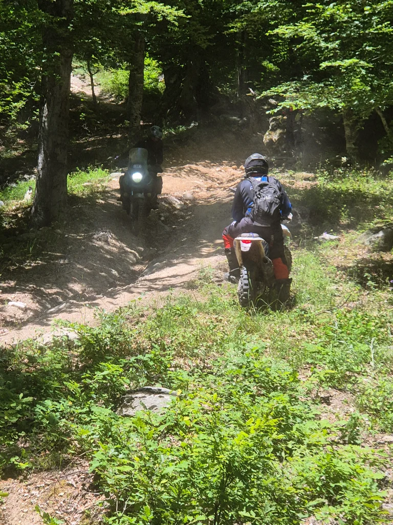 Adventure μοτοσυκλέτες σε δύσκολη χωμάτινη κατηφόρα στον Όλυμπο με πέτρες και νεροφαγώματα