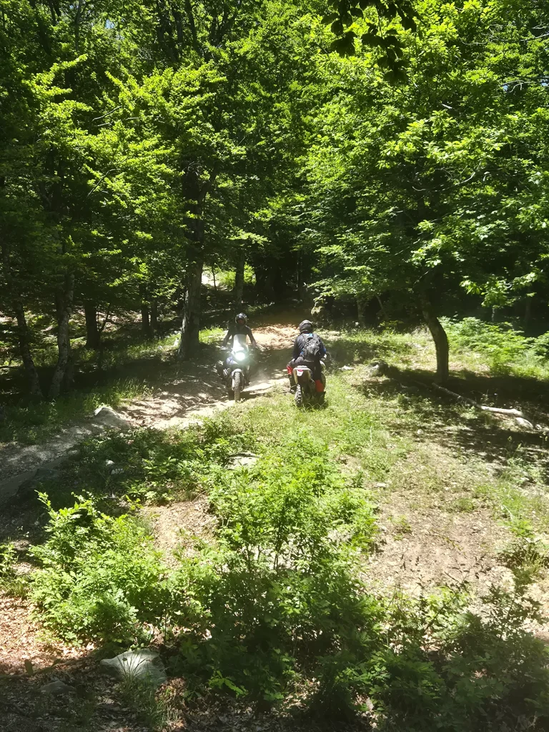 Adventure μοτοσυκλέτες σε απότομη χωμάτινη κατηφόρα στον Όλυμπο με πέτρες και νεροφαγώματα